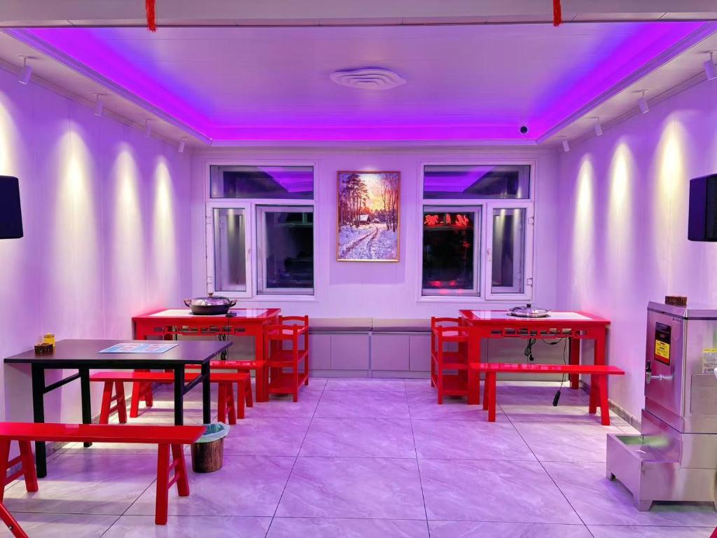 a dining room with red tables and purple lights at Snow Valley Ruixueju Boutique B&B in Huolonggou