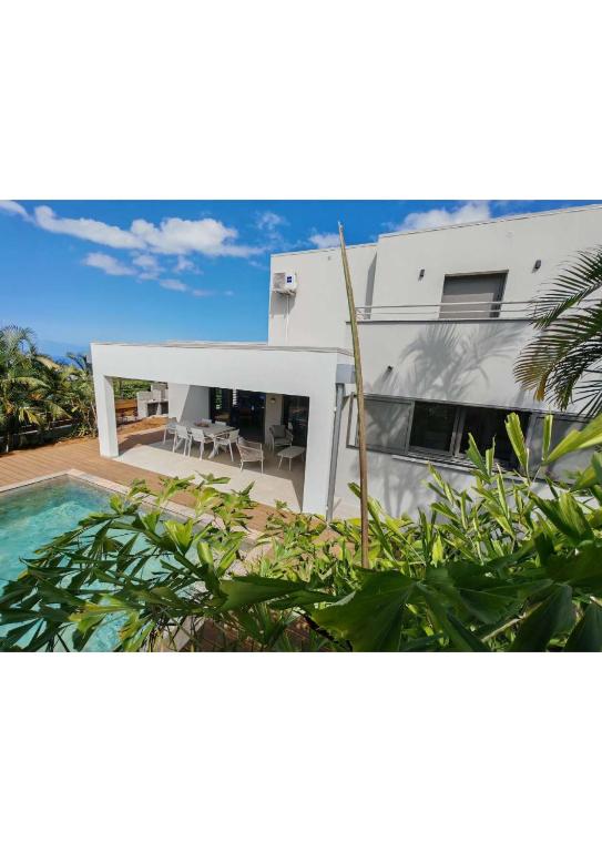 a white house with a swimming pool in front of it at Villa Emeraude in Saint-Louis
