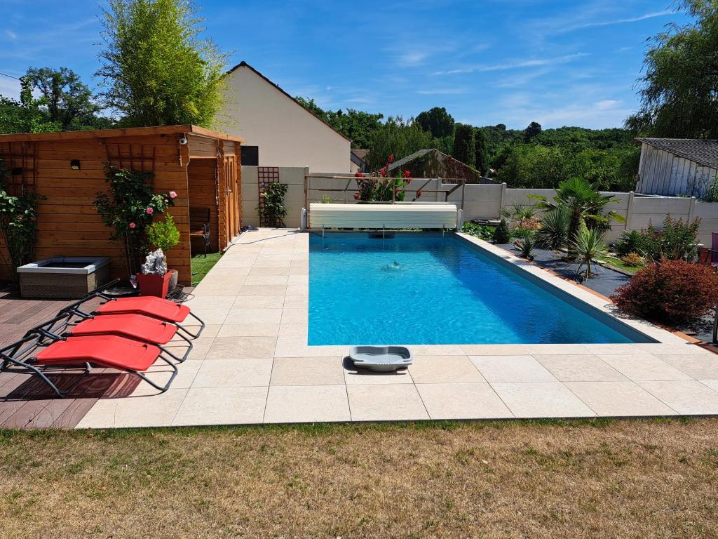 a swimming pool with red chairs in a backyard at La Vallée du Cher in Monthou-sur-Cher