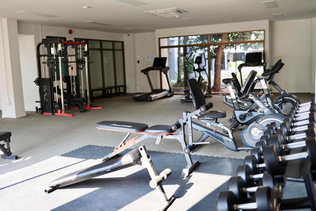 A bright hotel gym with cardio machines, weight equipment and a large window.