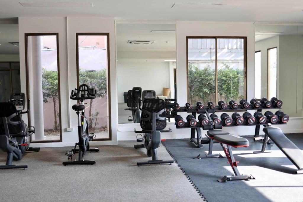 A bright hotel gym with cardio machines, free weights and benches.