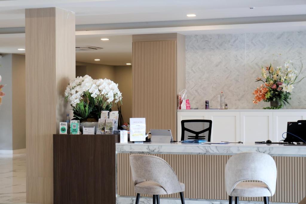 A compact front desk with two guest chairs and floral displays.