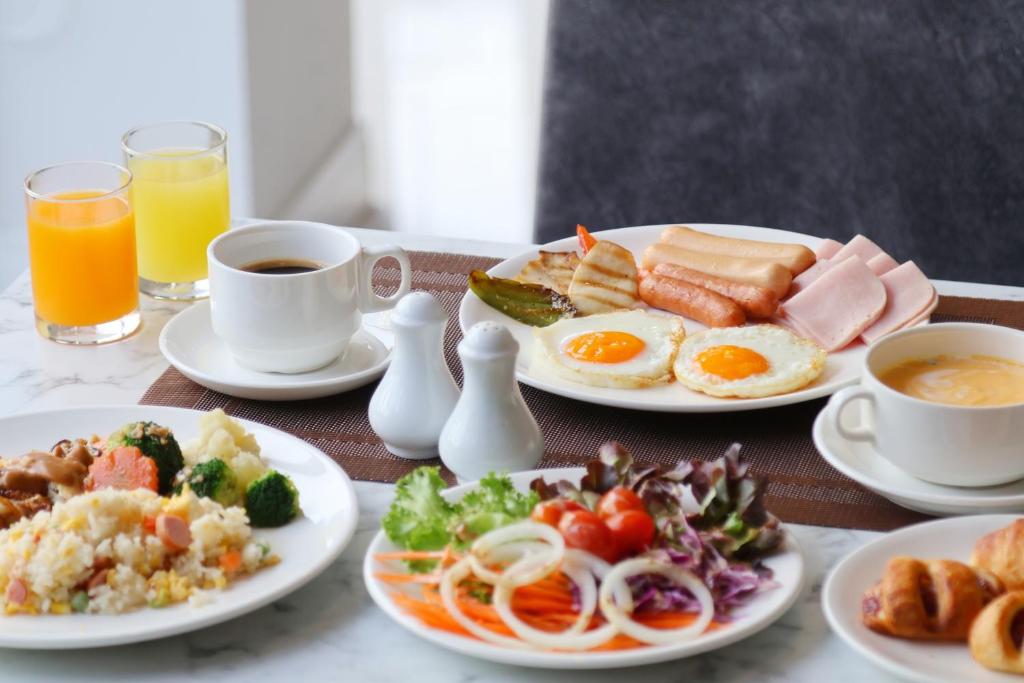 A plated breakfast spread with eggs, meats, rice, salad, pastries, juice and coffee.