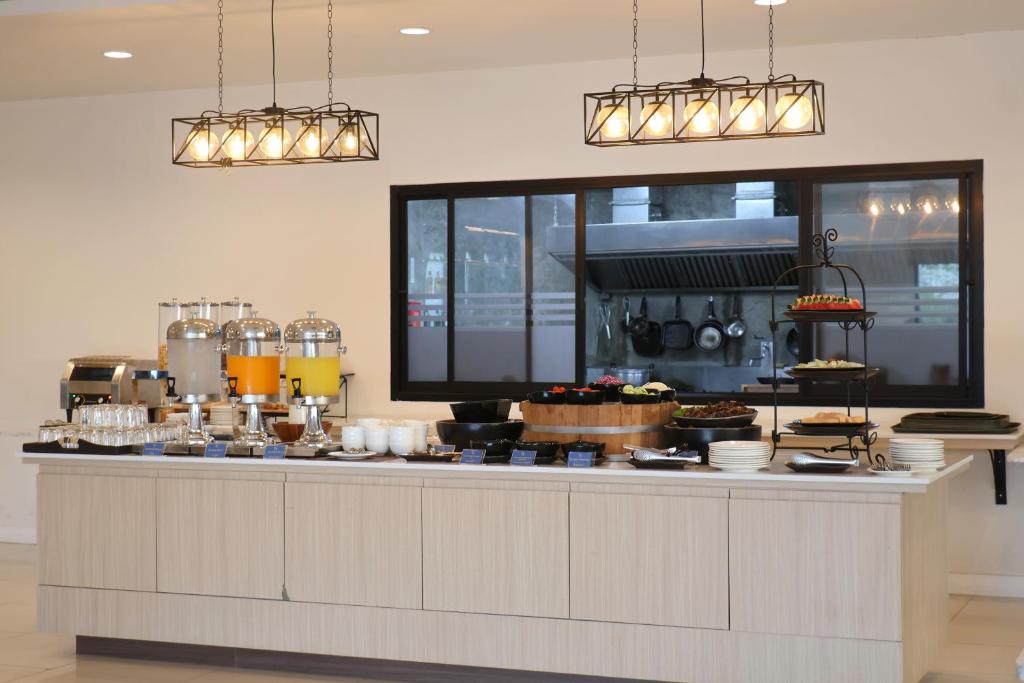 A buffet counter presents drinks, crockery, plated dishes and a tiered pastry stand in front of the kitchen.