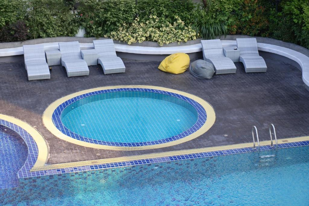 A pool deck with a small circular pool, loungers and dense greenery.