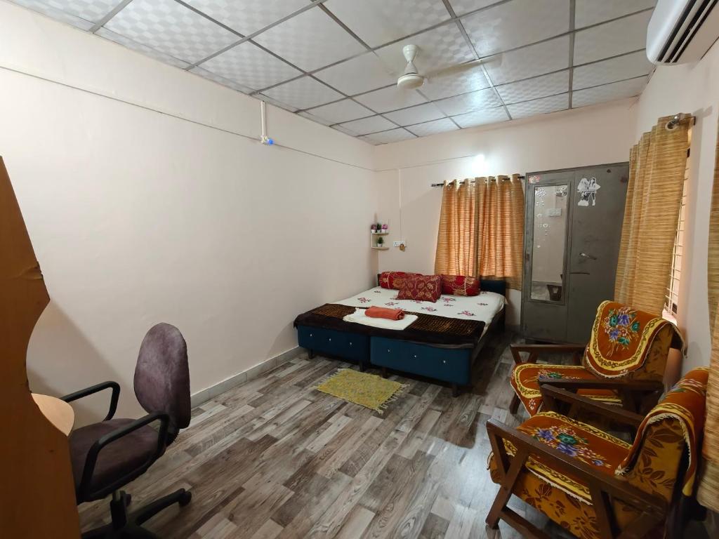 a living room with a bed and chairs in it at Prime Area 1AC Room Budget Stay in Bhopal