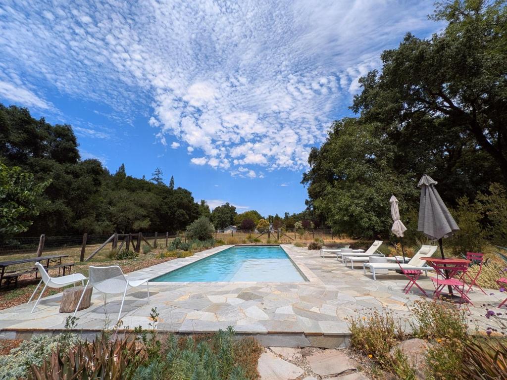 a swimming pool with chairs and an umbrella at Healdsburg Homestead A Wine Country Escape in Healdsburg