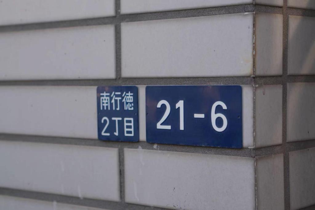 een blauw bord aan de zijkant van een bakstenen muur bij D Regalo in Ichikawa