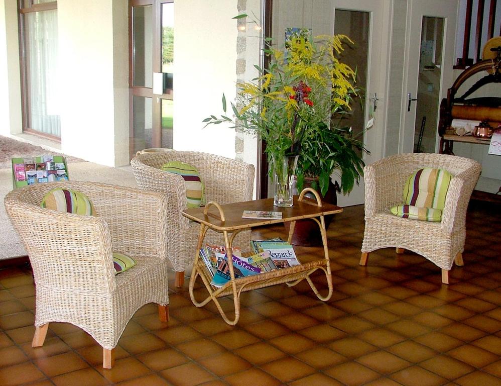 uma sala de estar com cadeiras de vime e uma mesa em Auberge d'Andaines em La Ferté-Macé