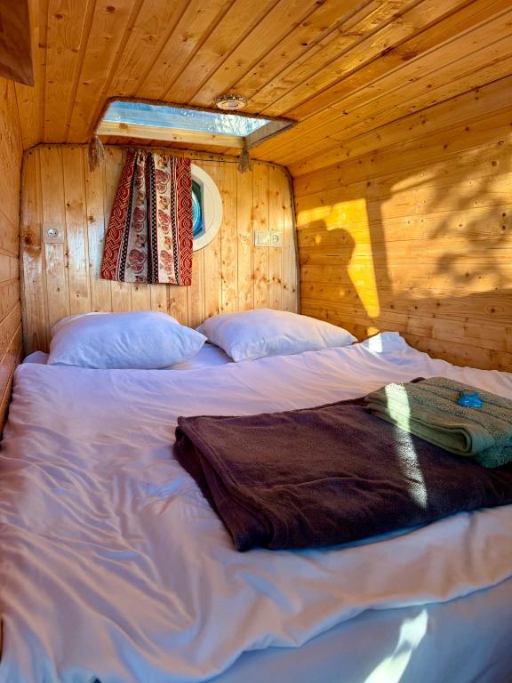a bed in a log cabin with a window at GeghardCamping in Goghtʼ