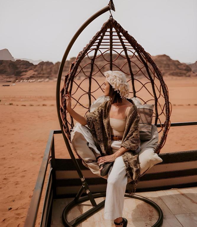 ワディ・ラムにあるCatalina Luxury rum campの砂漠のブランコに腰掛けた女