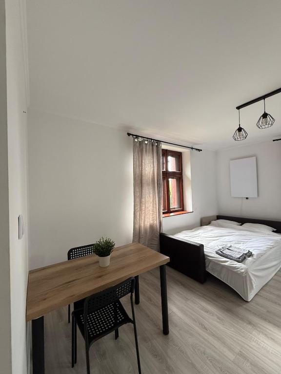 a bedroom with a bed and a table with a desk at Parkowa Apartment in Wadowice