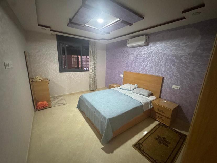une chambre avec un lit et un mur violet dans l'établissement Wassime location, à Taourirt