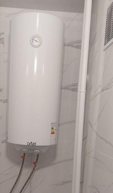 El baño incluye ducha con tanque blanco. en Квартира, en Pavlodar