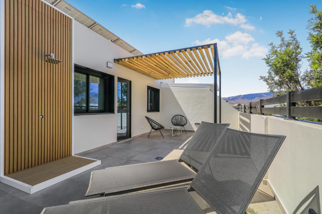 an outdoor patio with chairs and a balcony at Penthouse City Hub Stay in Vecindario