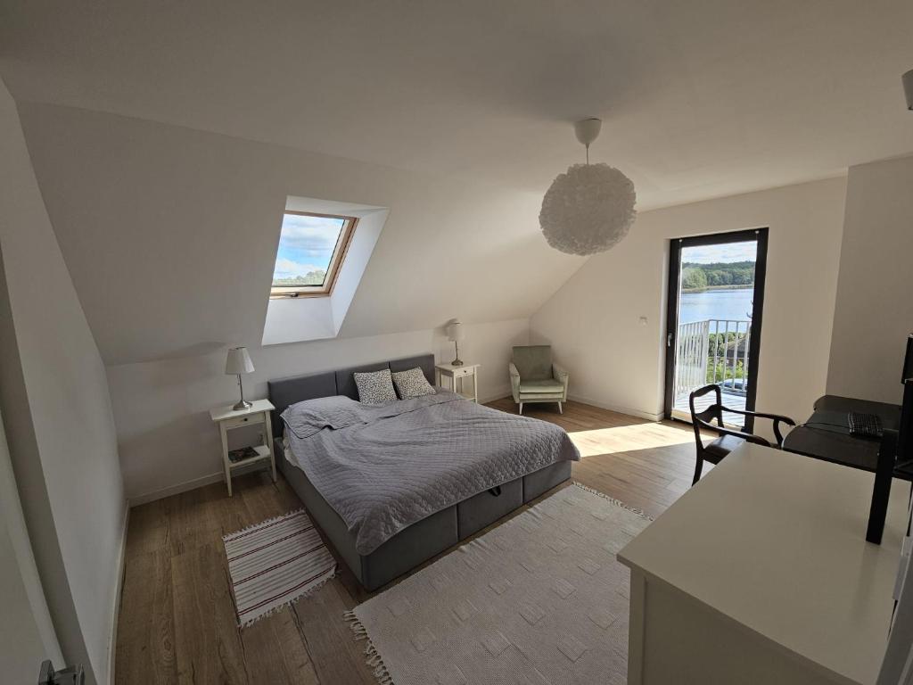 a white bedroom with a bed and a balcony at W Tarczynach - mazurski dom z widokiem na jezioro in Tarczyny
