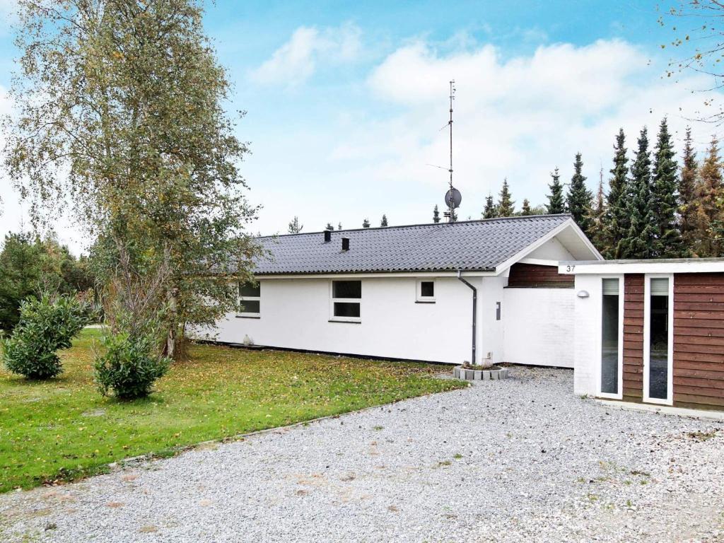 une maison blanche avec une allée devant dans l'établissement 10 person holiday home in Væggerløse, à Bøtø By