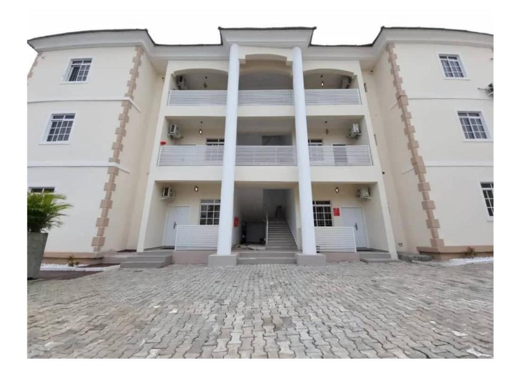 a large white building with columns and a courtyard at Fort Fountain Apartments in Abuja