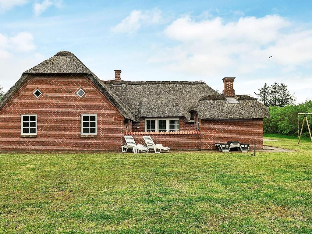 a large red brick house with two chairs in the yard at 18 person holiday home in Ulfborg in Ulfborg