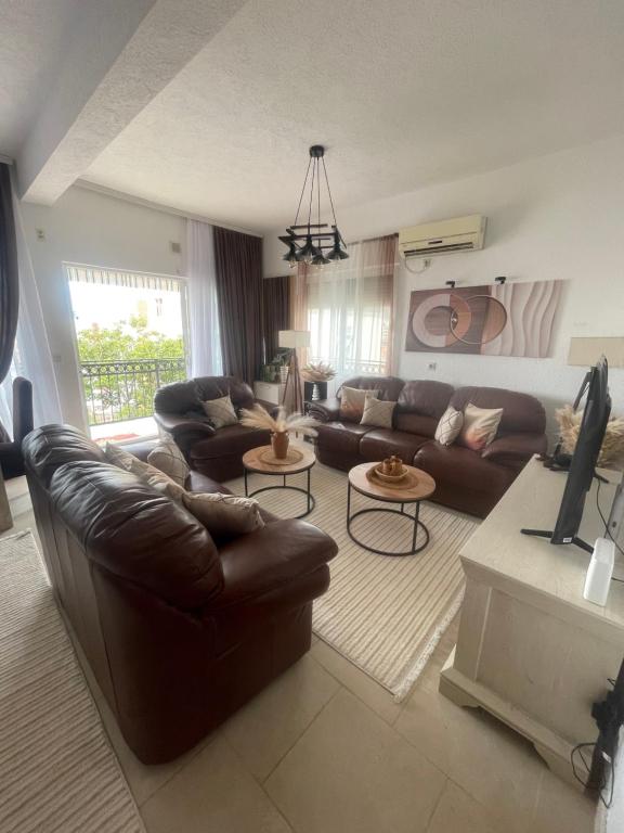 a living room with brown leather furniture and a tv at Lux Apartman David Dobra voda in Bar