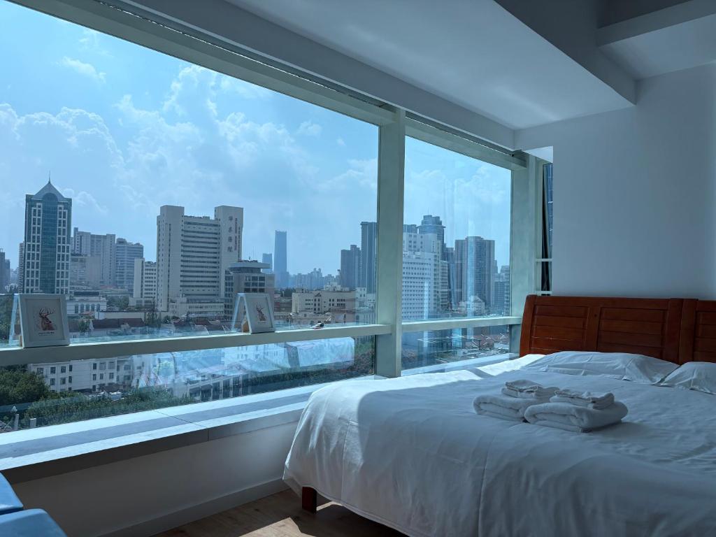 Schlafzimmer mit einem großen Fenster mit Stadtblick in der Unterkunft Fanhua Life IN Nanjing West Road Store 1 in Shanghai