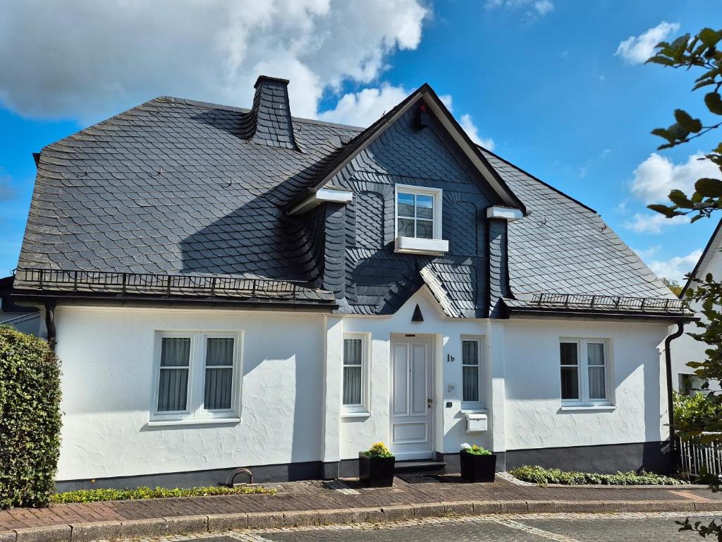 een wit huis met een zwart dak bij Fewo Schmallenberger Mauerblümchen in Schmallenberg