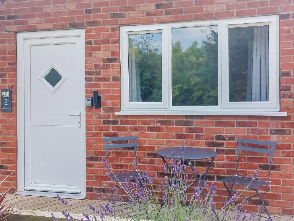 a brick house with a white door and a table and chairs at Kirkstead - Uk49438 in Walcot