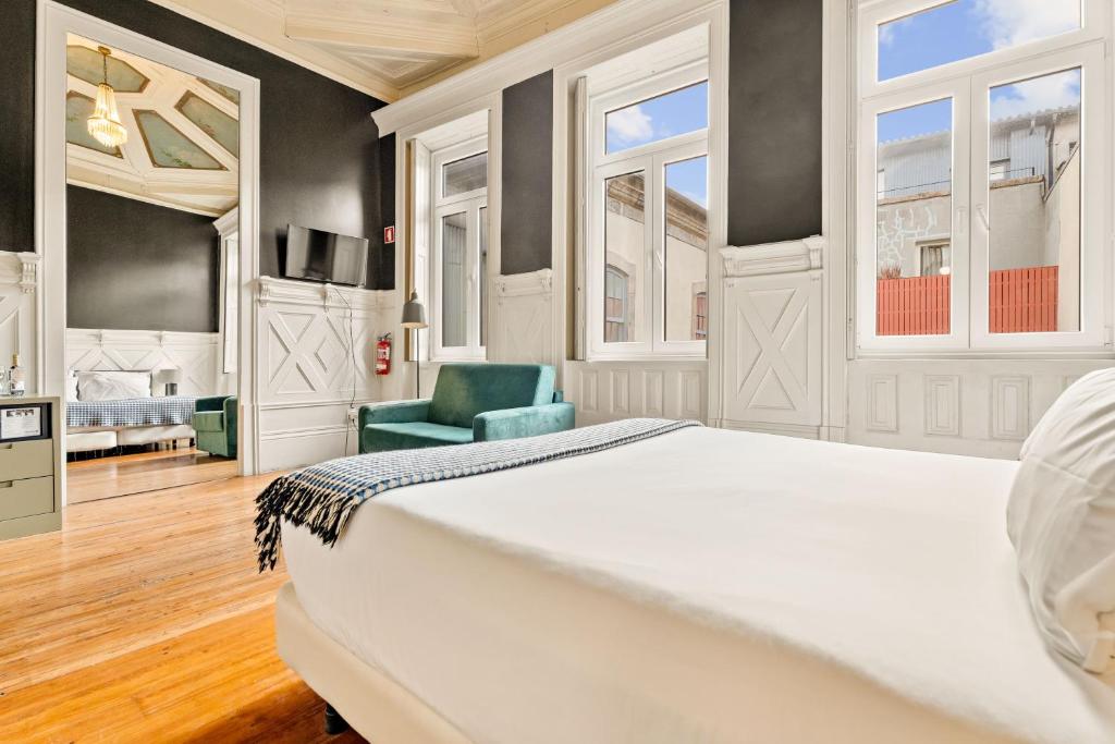 a bedroom with a white bed and a green chair at Casa dos Lóios by Shiadu in Porto