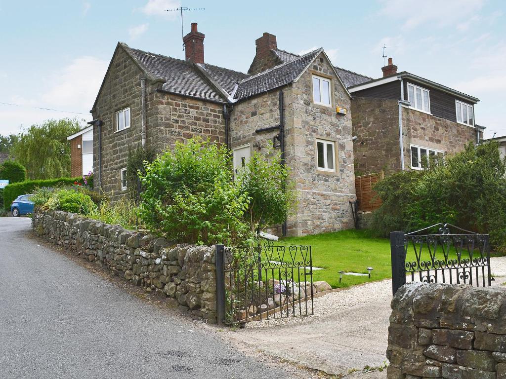 an old brick house with a stone fence at Post Office Cottage in Highpeak Junction