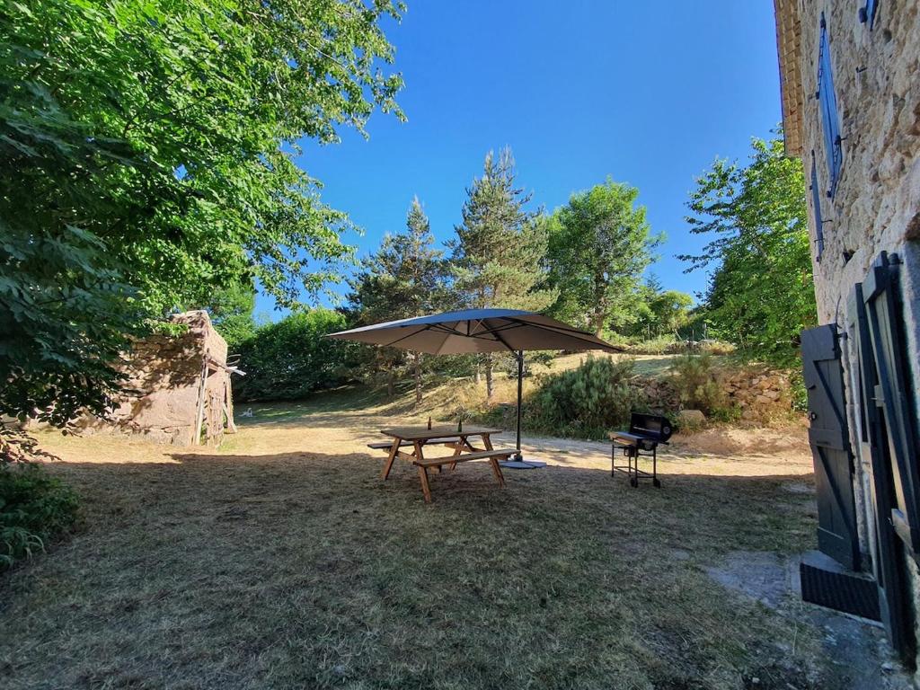 a picnic table with an umbrella and a chair at Le Clos d'Aboulin in Saint-Christophe-dʼAllier