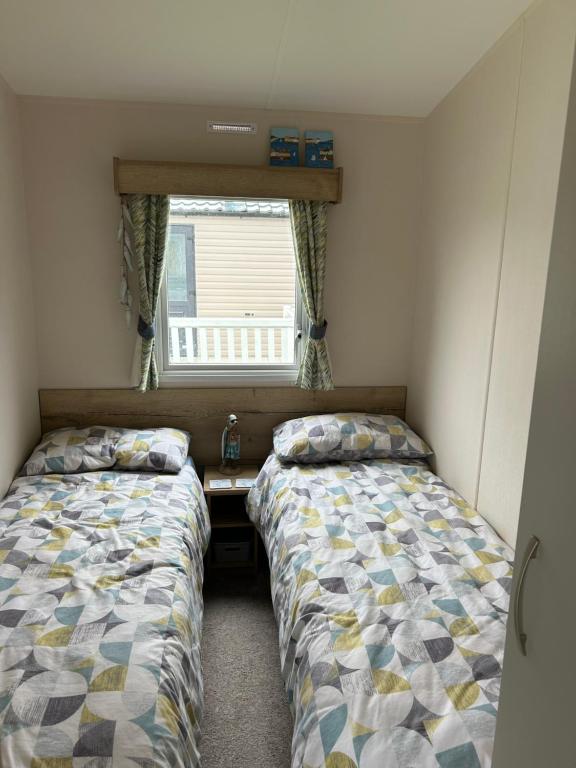 Dos camas en una habitación pequeña con ventana. en L20 at Seven Bays Park, en St Merryn