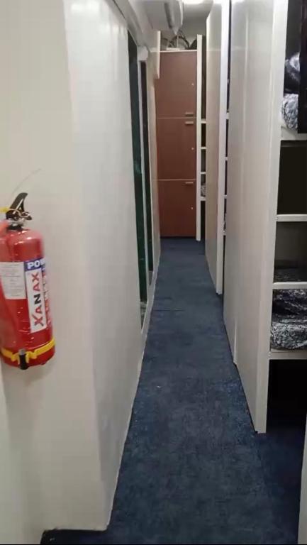 a hallway with a fire extinguisher on the wall at Kapoor dormitory in Mumbai