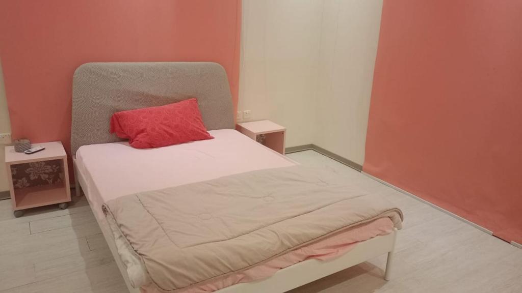 Un pequeño dormitorio con una cama con una almohada roja. en شاليه هاوس مون, en Al Rass