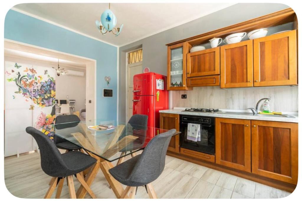 cocina con mesa de cristal y nevera roja en Confortable, en Trapani