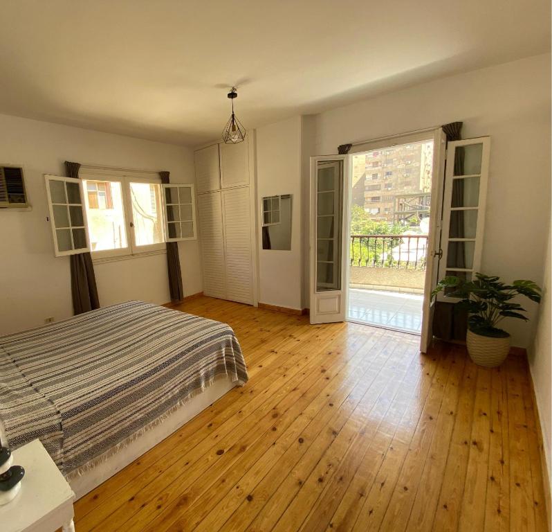 a bedroom with a bed and a wooden floor at Villa Maadi 35 -R 304- Balcony & Pool View Room in Cairo