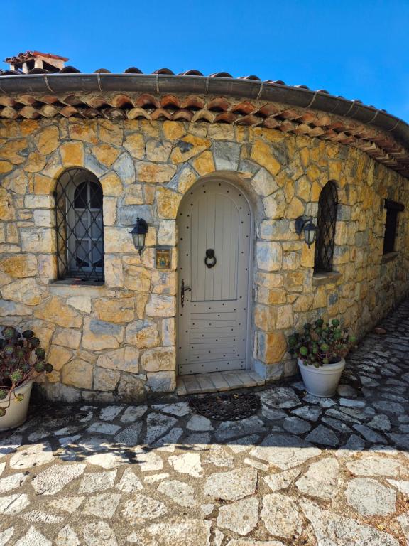 a stone building with a white door and two plants at La Ruchanne in Tourrettes-sur-Loup