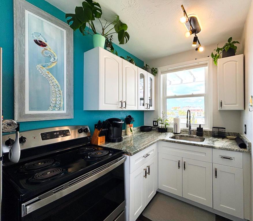 eine Küche mit weißen Schränken und einem schwarzen Herd mit Backofen in der Unterkunft Charming suite with private deck Downtown FMB in Fort Myers Beach