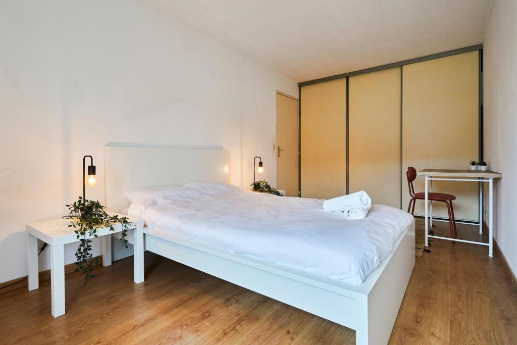 ein Schlafzimmer mit einem weißen Bett und einem Schreibtisch in der Unterkunft T2 spacieux - Lille Saint Maurice Pellevoisin in Lille