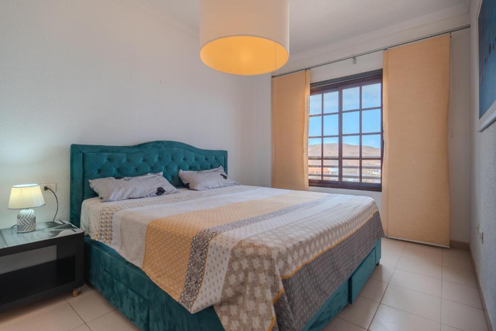 a bedroom with a bed with a green headboard and a window at Appartment Zomero, SEAVIEW & WIFI & POOL in Costa Del Silencio
