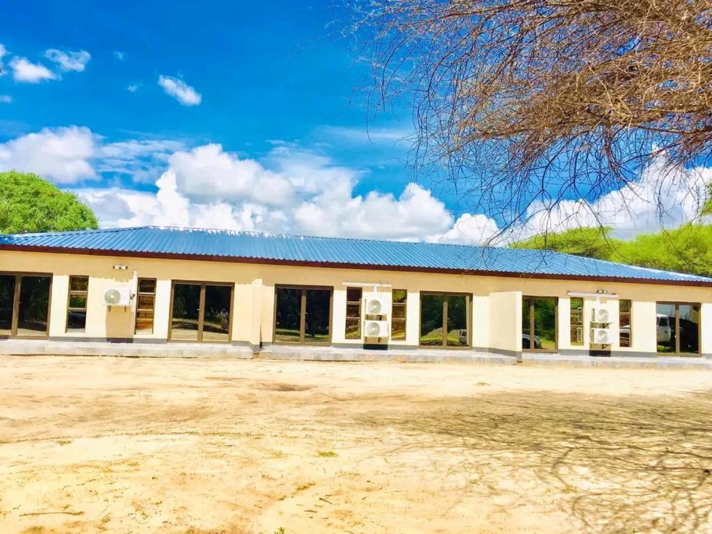 a large white building with a blue roof at Atoma Lodge in Shakawe