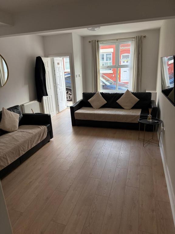 een woonkamer met een bank en een houten vloer bij Two bedroom house free parking in Liverpool
