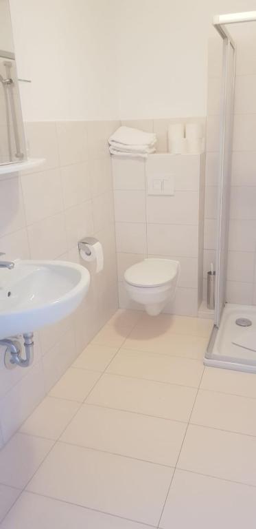 a white bathroom with a toilet and a sink at A & M Apartments in Hildesheim