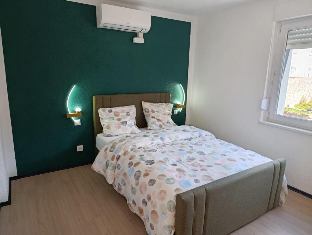 a bedroom with a bed with a green wall at NG-Global Home in Sierentz