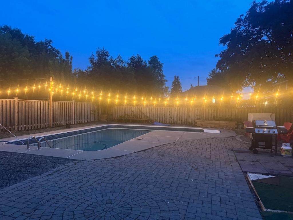 a swimming pool with lights on a fence at night at Poolside Retreat with Private Patio in Brampton