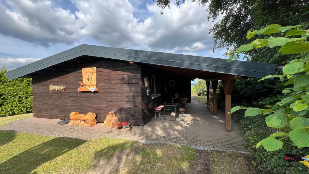 a small building with a black roof on a yard at Ferienwohnung Van den Bergh in Bromskirchen