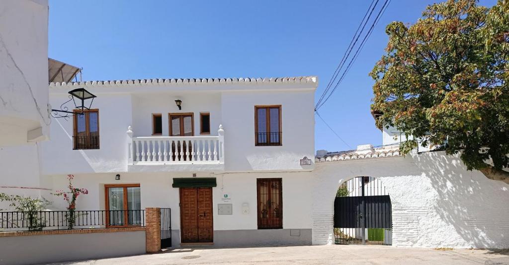 une maison blanche avec un balcon au-dessus dans l'établissement Casa El Molino de Melegis - Lecrin Valley, à Melegis