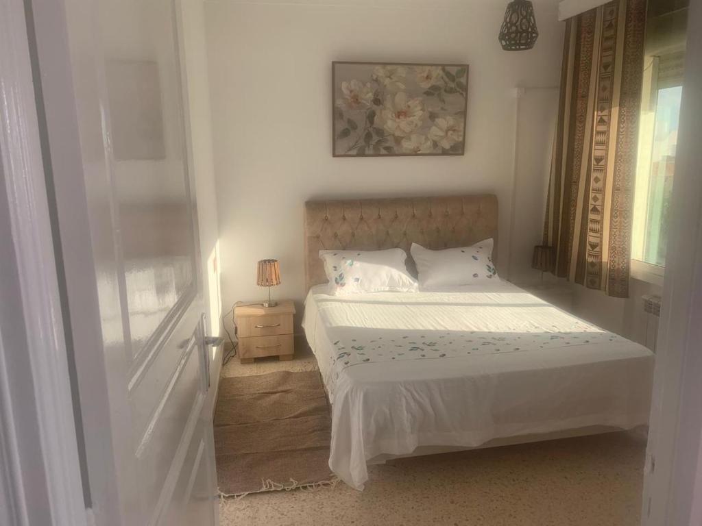 una camera da letto bianca con un letto e una finestra di home zeinbe 2 a Hammamet