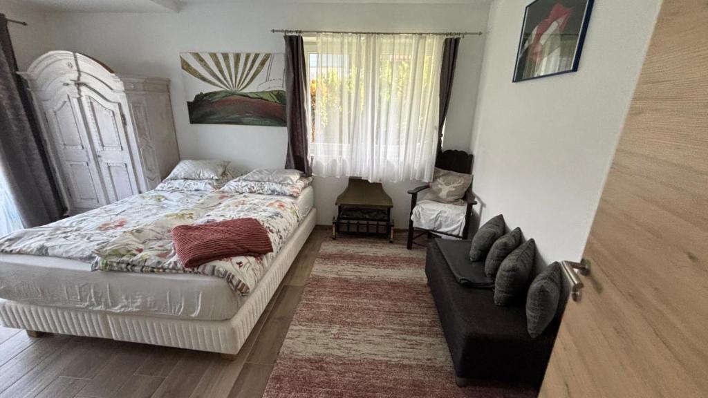 a bedroom with a bed and a couch and a window at Smaragdherz in Bramberg am Wildkogel