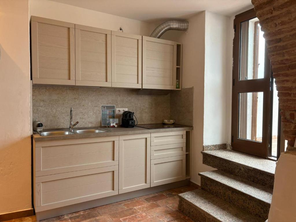 a kitchen with white cabinets and a sink next to a window at Sa meraviglia in Posada
