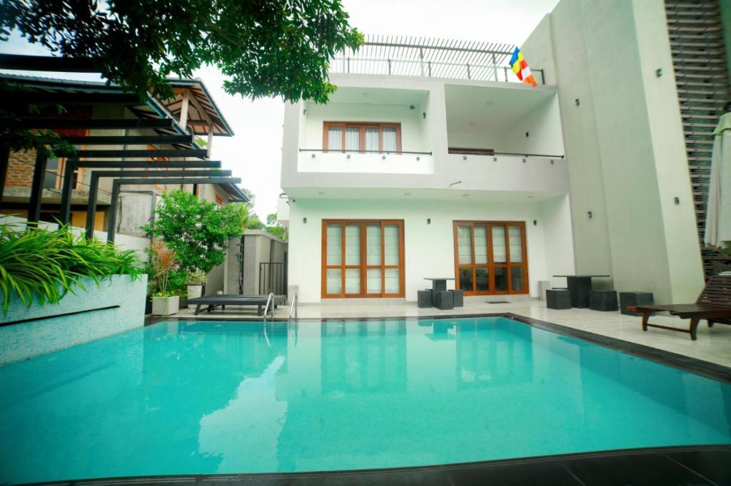 a swimming pool in front of a house at Stadler Resort in Wadduwa
